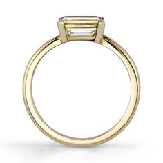 a yellow gold engagement ring with a baguette cut diamond in the center and side stones