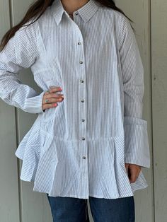 Made from 100% cotton, the Brynlee Ruffle Tunic Shirt is perfect for any season. Its lightweight material and cuffed sleeves provide both comfort and style. The versatile design features a ruffle bottom and can be worn open or closed with buttons down the front. Elevate your wardrobe with this striped must-have! Measurements S: bust 40" length 29" shoulders 15" M: bust 44" length 31" shoulders 16" L: bust 48" length 33" shoulders 17" Cotton Shirt For Spring Daywear, Spring Long Sleeve Tops With Ruffle Hem, Relaxed Fit Cotton Blouse With Ruffle Sleeves, Spring Tops With Ruffle Hem And Ruffled Collar, Ruffled Collar Top With Ruffle Hem For Day Out, Relaxed Fit Blouse With Ruffle Sleeves And Details, Ruffle Sleeve Blouse With Relaxed Fit, Casual Cotton Blouse With Ruffle Sleeves, Cotton Tops With Ruffle Sleeves For Daywear