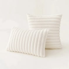 several white pillows stacked on top of each other in front of a white wall and floor