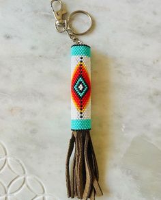 a keychain with a beaded design and tassel hanging from it's side