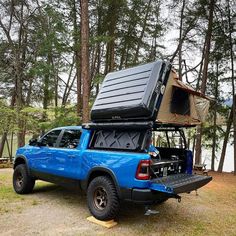 a blue truck with an open back and luggage strapped to it's bed in the woods