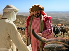 a man in a red and white outfit standing next to two men with long horns