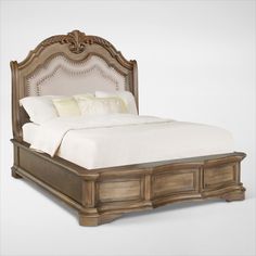 a bed that is made up and has white sheets on top of it, with an ornate headboard