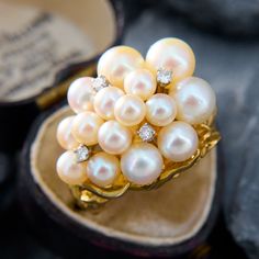 This scrumptious vintage cluster ring features an organic design that is post set with fifteen (15) saltwater Akoya pearls, and four (4) prong set round brilliant cut diamond accents. The ring measures 18.3mm at the top, rises 14.9mm above the finger, tapering to 3.5mm wide and 1.7mm thick at the base of the shank. It is crafted in 18k yellow gold and is currently a size 4.5. Fine Jewelry Cluster Pearl Ring For Anniversary, Fine Jewelry Pearl Cluster Ring For Wedding, Anniversary Fine Jewelry Pearl Cluster Ring, Cluster Pearl Wedding Ring, Wedding Pearl Cluster Ring, Wedding Cluster Pearl Ring, Multi-stone Diamond Pearl Ring For Wedding, Classic Cluster Pearl Ring For Wedding, Elegant Cluster Pearl Ring Gift