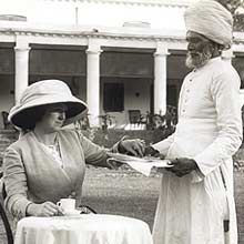 an old black and white photo of two women sitting at a table in front of a house