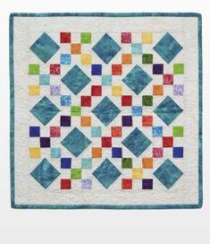 a colorful quilt is hanging on the wall in front of a white background with blue and green squares