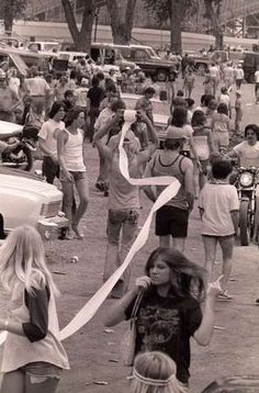 a group of people walking down a street next to parked cars