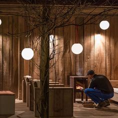 a man kneeling down next to a fire place in a room with wooden paneling