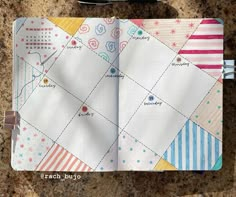 an open notebook with paper and scissors on the table next to it, which has been made into a patchwork quilt