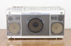 an old fashioned radio with two speakers on it's front and back sides, sitting on a wooden floor