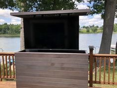 an outdoor entertainment center on a deck next to a lake