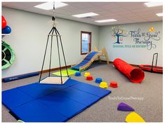 an indoor play area with swings, slides and climbing mats for children to climb on