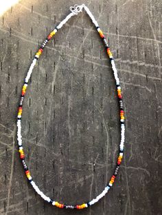 White, light blue, black, red, orange, and yellow beaded necklace. Southwestern Black Beaded Necklaces For Festivals, Southwestern Style White Beaded Necklace With Large Beads, Handmade Southwestern Black Beaded Necklace, Adjustable Southwestern Beaded Necklace With Black Beads, Southwestern Black Beaded Necklace For Festivals, Adjustable Multicolor Beaded Necklaces With Black Beads, Southwestern Orange Beaded Necklaces With Round Beads, White Southwestern Style Beaded Necklaces For Festival, Southwestern Style Black Beaded Bracelet With Colorful Beads