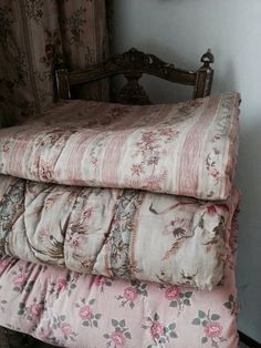 three pillows stacked on top of each other in front of a chair with floral fabric