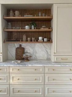 a kitchen with white cabinets and marble counter tops, gold pulls on the cupboards