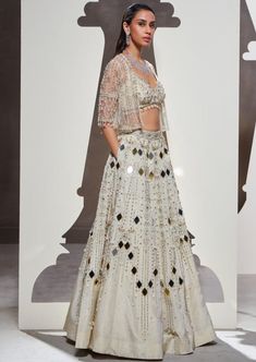 Dripping with eclectic mirror embellishments, scintillating silhouettes, and luxurious fabrics, our anora lehenga set is a masterpiece of sartorial artistry. The set features an opulently handcrafted lehenga and a stunning blouse, elegantly paired with a heavily embellished short jacket. Lehenga Blouse With Jacket, White Sequin Sets For Eid, Traditional Sequin Palazzo Set For Reception, Traditional Palazzo Set With Sequins For Reception, Unstitched Hand Embellished Sets For Diwali, Festive Sequined Palazzo Set For Reception, Hand Embellished Unstitched Sets For Diwali, Festive Semi-stitched Hand Embellished Palazzo Set, Festive Hand Embellished Semi-stitched Palazzo Set