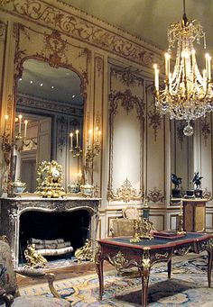 an ornately decorated living room with chandelier and fireplace