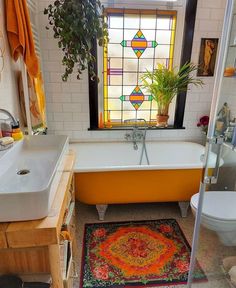 a bath room with a tub a sink and a rug on the floor in front of a window