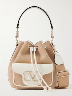 You'll want to bring Valentino Garavani's 'Locò' bucket bag on all your tropical vacations, and it'll look unexpectedly cool in the city as well. Woven from raffia, it's trimmed in white leather and features the signature 'VLOGO' in gold-tone metal. Carry it by your choice of the shorter or longer strap and stow your phone, cardholder and a few makeup essentials inside. Luxury Bucket Bag With Leather Trim, Valentino Bucket Bag, Luxury Beige Basket-shaped Bucket Bag, Luxury Basket-shaped Bucket Bag, Luxury Bucket Bag With Adjustable Strap For On-the-go, Bucket Bag Style, Valentino Garavani Bag, Eyewear Shop, Drawstring Bucket Bag