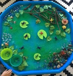 a child's hands holding a blue tray filled with water and plants