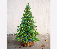 a small christmas tree made out of beads in a wicker basket on the ground