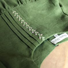 a close up of a green shirt with flowers on it