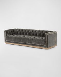 a grey velvet sofa with wooden legs