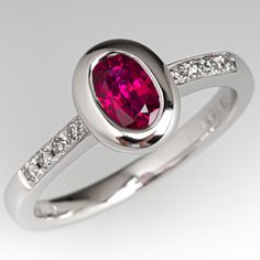 This lovely ring is centered with one (1) oval cut natural ruby set into a bezel setting. The top face of the shank is accented with a row of four (4), prong set, round brilliant cut diamonds on each side. The ring measures 8.6mm at the top, rises 5.0mm above the finger, tapering to 2.3mm wide and 1.5mm thick at the base of the shank. This ring is currently a size 6.5. Oval Ruby Ring With Diamond, Formal Ruby Ring With Oval Cabochon Center Stone, Timeless Oval Ruby Ring With Diamonds, White Gold Ruby Ring With Accent Stones, Oval Shaped, Elegant Ruby Ring With Polished Finish, Elegant Ruby Ring With Oval Diamond, Formal Ruby Ring With Oval Cabochon, Oval Brilliant Cut Ruby Promise Ring, Classic Ruby Ring With Diamond And Polished Finish