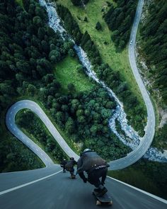 two people riding skateboards down a winding road