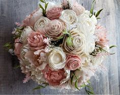 a bouquet of pink and white flowers sitting on top of a wooden table