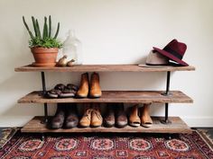 shoes are lined up on three shelves in front of a rug and potted plant