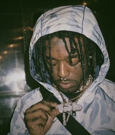 a young man with dreadlocks and a cross on his chest wearing a hoodie