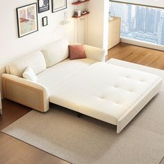 a white couch sitting on top of a rug in a living room next to a window