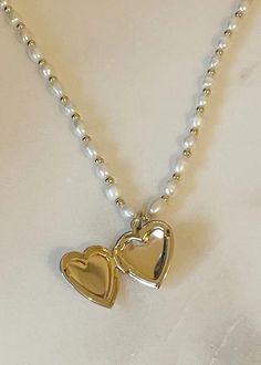 - Gold and pearl heart locket necklace - 14K gold filled, freshwater pearls SIZE NOTES - 15.5" long - 5mm freshwater pearl chain SUSTAINABLY MADE - From House of Au. + ORA (Costa Mesa, California) - Sustainable Values: #7: Safe, livable, dignified employment SUSTAINABLE CARE - Gold filled jewelry will not tarnish, but may become dirty over time. To clean, use mild dish soap, hot water, and a gentle cloth. Heart Jewlery, Pearl Locket, Costa Mesa California, Jewellery Pearl, Gold Locket Necklace, Heart Locket Necklace, Pearl Heart, Gold Locket, Gold Pearl Necklace