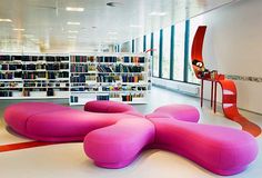 a large pink couch sitting in the middle of a library