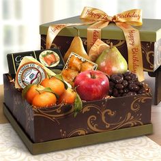 a gift box filled with assorted fruit, nuts and chocolates on a table