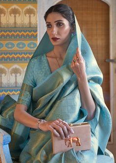 a woman in a blue sari is holding a purse and posing for the camera