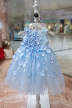 Dress your little princess in enchanting elegance with our Flower Girls' Light Blue Dress! This ballgown is a dream come true, boasting a sleeveless empire waist silhouette, round neckline, and a mesmerizing floor-length multilayer tulle skirt that twirls with every step. 🌸✨ Adorned with exquisite ombré white and soft light blue 3D appliqué flowers, as well as delicate white feathers, this dress is a true masterpiece. 🎀💙 Fully lined with 100% cotton for comfort, it features an invisible zippe Appliqué Flowers, Flower Girl Dresses Blue, Sky Blue Dress, Light Blue Dress, Light Blue Dresses, Baby Boy Romper, A Dream Come True, White Feathers