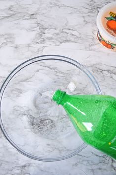 an empty plastic bottle in a glass bowl on a marble counter top next to a container of carrots