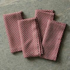 three red and white napkins sitting on top of a gray counter next to each other