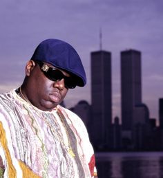 a black and white photo of a man with sunglasses on his face, in front of a cityscape