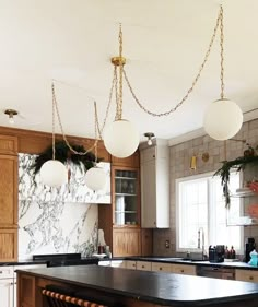 a kitchen with marble counter tops and hanging lights over the stove top island in front of an oven