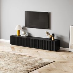 a flat screen tv mounted to the side of a wall next to a lamp and rug