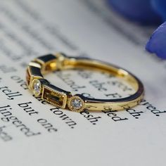 a close up of a ring on top of an open book with flowers in the background