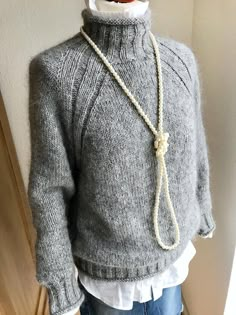 a mannequin wearing a gray sweater with a white collar and rope around the neck