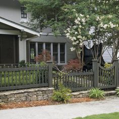 a house with a fence and flowers in the front yard