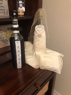 a bottle of liquor and wedding dress on a dresser with a bride's veil