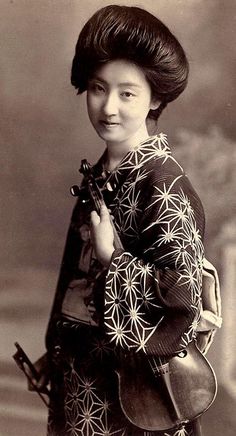 an old black and white photo of a woman in kimono holding a small camera