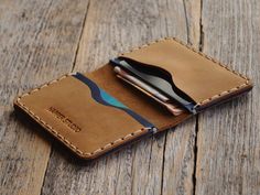 "You want a wallet that fits everything without adding an extra two inches to your pocket. Style and functionality meet with this sleek, hand-sewn bovine leather wallet. Four strategically placed pockets inside the rustic genuine leather pouch keeps all of your everyday essentials organized and ready to grab. Each of our wallets is handmade out of quality leather that naturally has inconsistent texture and markings creating a unique wallet for you or your loved one. Personalize this stylish, uni Leather Working Projects, Blue Leather Wallet, Unique Wallets, Personalized Leather Wallet, Slim Leather Wallet, Leather Ideas, Brown And Blue, Baseball Glove, Money Clip Wallet