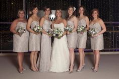 a group of women standing next to each other wearing dresses and holding bouquets in their hands